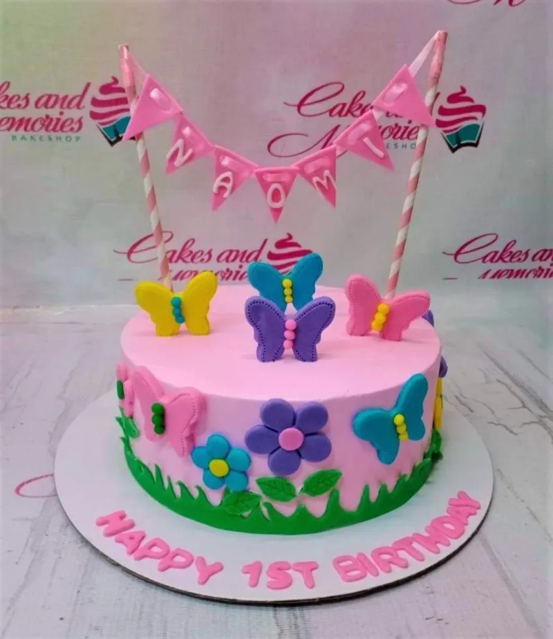 Pink butterfly and flower birthday cake with a pink banner topper and colorful fondant decorations. Pink butterfly and flower birthday cake with a pink banner topper and colorful fondant decorations.