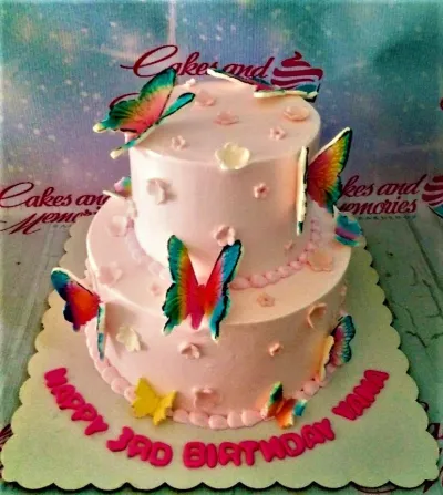 Pink two-tier butterfly birthday cake with colorful butterfly toppers and small pink and white fondant flowers. Pink two-tier butterfly birthday cake with colorful butterfly toppers and small pink and white fondant flowers.