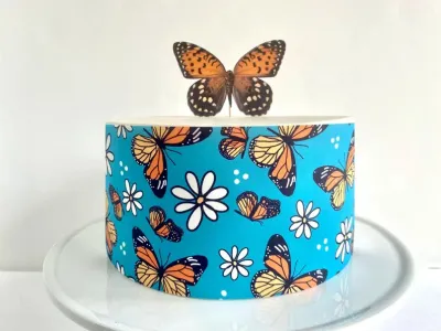 Teal butterfly and daisy themed cake with a large monarch butterfly topper and matching side wrap design. Teal butterfly and daisy themed cake with a large monarch butterfly topper and matching side wrap design.