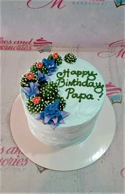 A light blue 1-tier cake themed around cactus, featuring green piped cacti, blue succulents, orange flowers, and a "Happy Birthday Papa" message. A light blue 1-tier cake themed around cactus, featuring green piped cacti, blue succulents, orange flowers, and a "Happy Birthday Papa" message.