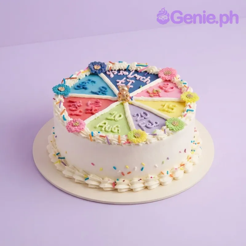 White 1-tier cake with piped icing segments, each featuring a date, and a small gold bear topper. White 1-tier cake with piped icing segments, each featuring a date, and a small gold bear topper.