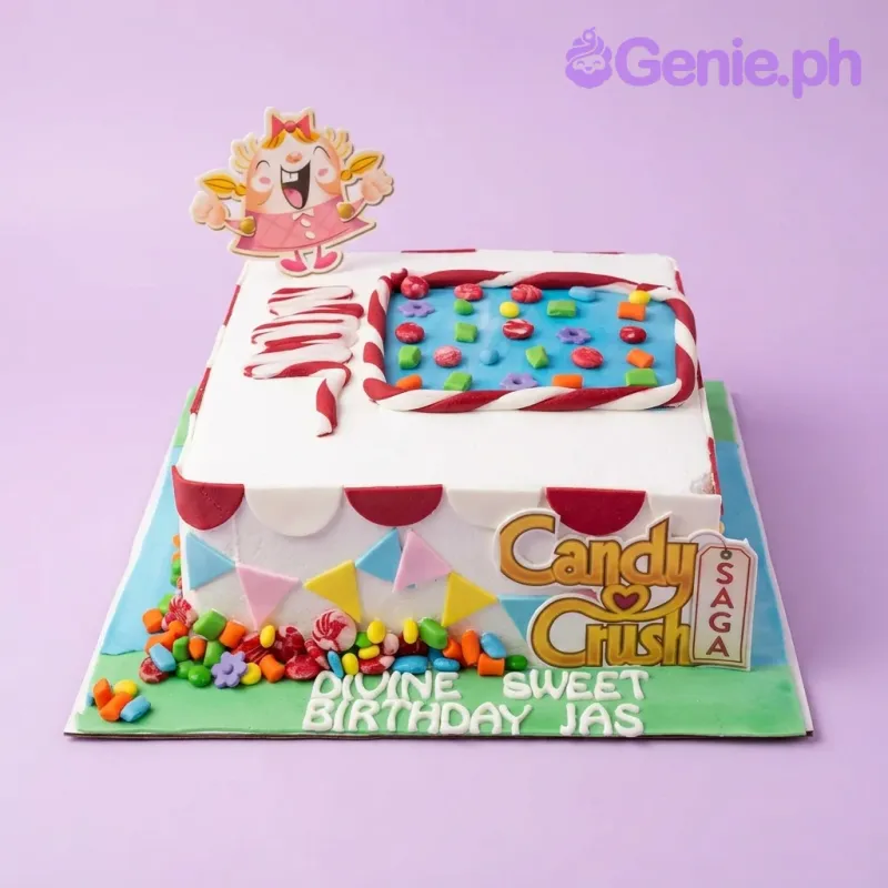 A white and green square Candy Crush Saga cake, with Tiffi and logo toppers, colorful candies, and a blue game board panel. A white and green square Candy Crush Saga cake, with Tiffi and logo toppers, colorful candies, and a blue game board panel.