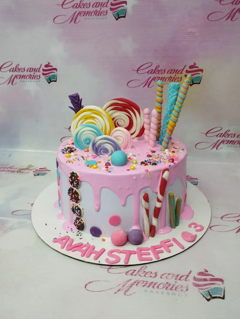 Pink and white candy-themed cake with colorful fondant lollipops, candy canes, and sprinkles. Pink and white candy-themed cake with colorful fondant lollipops, candy canes, and sprinkles.
