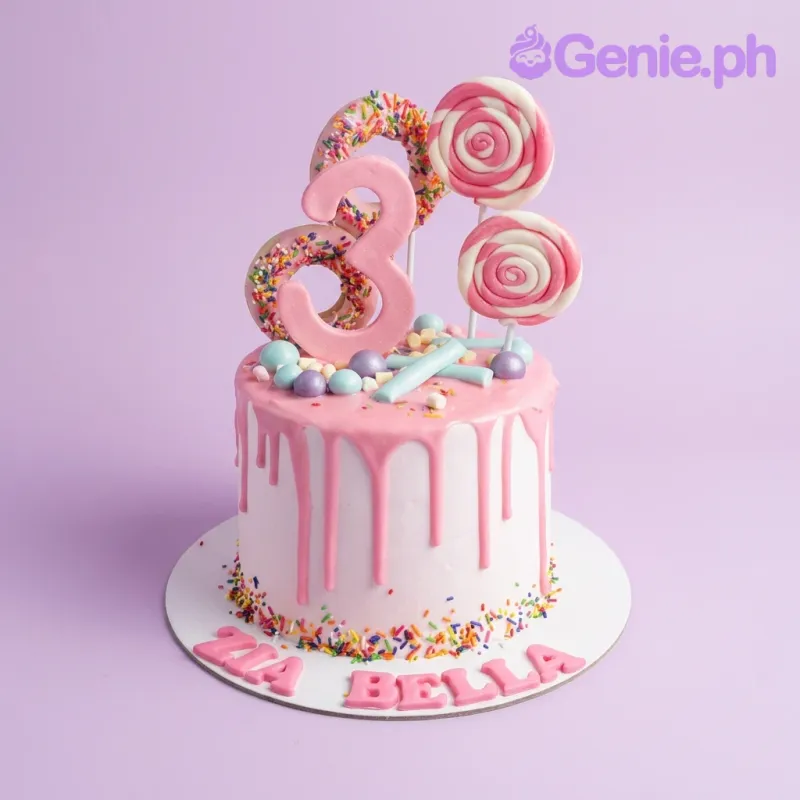 A pink 1-tier cake, Candy Theme, with a large pink number 3, swirl lollipops, pink donuts, multicolor sprinkles, and 'ZIA BELLA' text. A pink 1-tier cake, Candy Theme, with a large pink number 3, swirl lollipops, pink donuts, multicolor sprinkles, and 'ZIA BELLA' text.