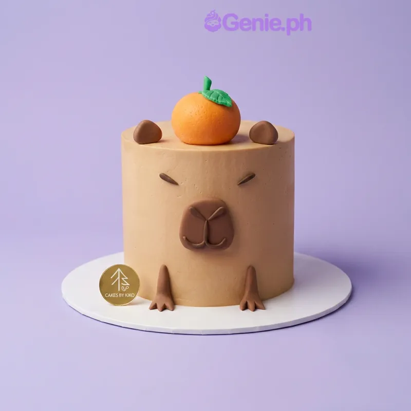 Tan round fondant cake decorated as a capybara with an orange on top Tan round fondant cake decorated as a capybara with an orange on top