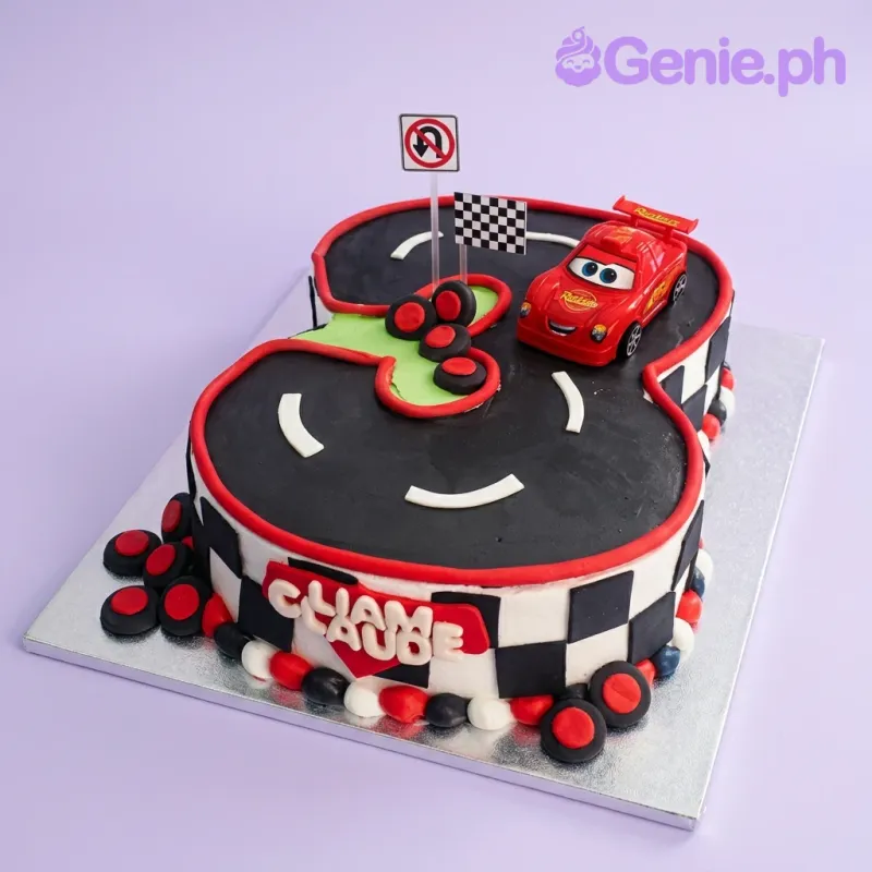 Number 8 shaped Cars themed birthday cake with Lightning McQueen toy car on a black fondant racetrack with checkered flag and road signs. Number 8 shaped Cars themed birthday cake with Lightning McQueen toy car on a black fondant racetrack with checkered flag and road signs.