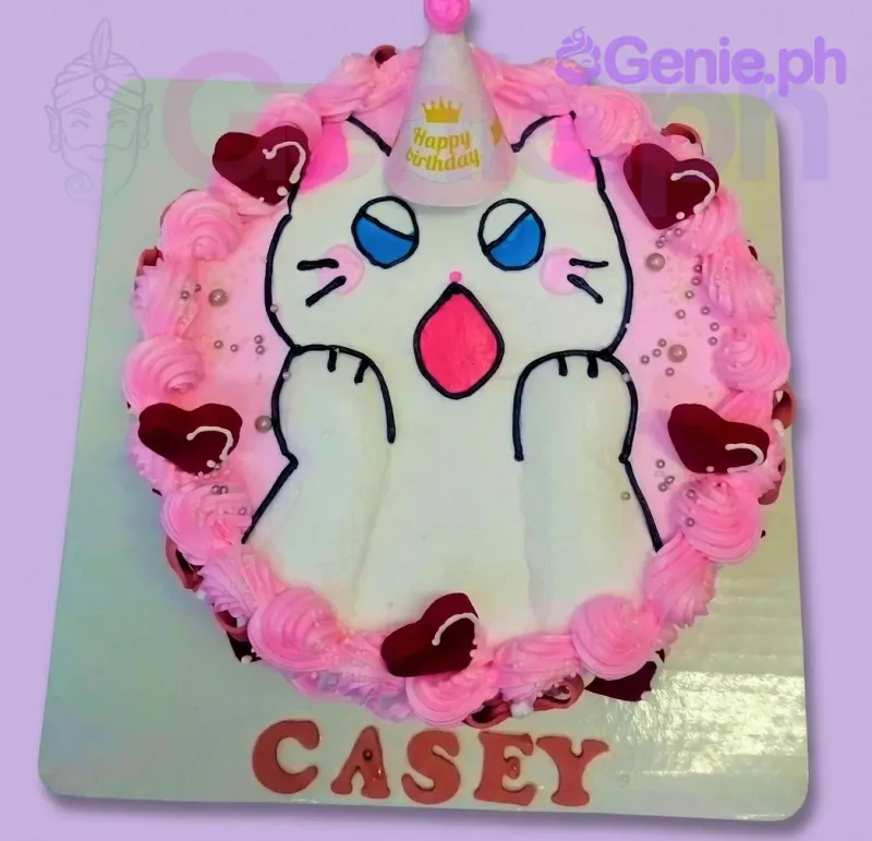 Bento cake featuring a white cat with a pink party hat and red hearts, surrounded by pink icing rosettes and silver pearls. Bento cake featuring a white cat with a pink party hat and red hearts, surrounded by pink icing rosettes and silver pearls.