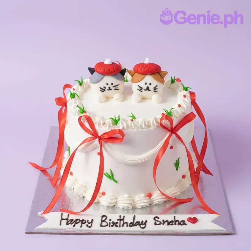 A white 1-Tier cake themed around Cat Birthday, featuring two cat toppers wearing red berets, red ribbons, and green icing accents. A white 1-Tier cake themed around Cat Birthday, featuring two cat toppers wearing red berets, red ribbons, and green icing accents.