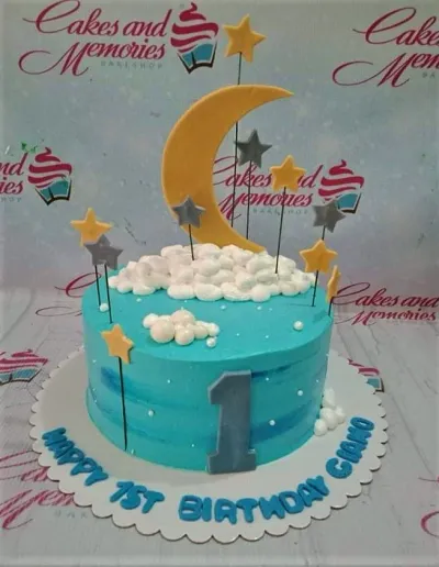 Light blue celestial birthday cake with a large yellow crescent moon, stars on sticks, and white icing clouds. Light blue celestial birthday cake with a large yellow crescent moon, stars on sticks, and white icing clouds.