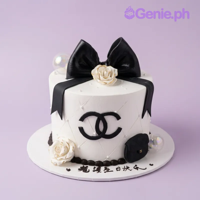 White 1-tier fondant cake with black bow, sculpted bag, a logo, white roses, and black piped border White 1-tier fondant cake with black bow, sculpted bag, a logo, white roses, and black piped border