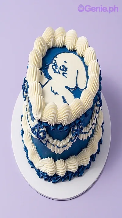 Navy blue and white round cake with a piped icing character drawing on top and a shell border Navy blue and white round cake with a piped icing character drawing on top and a shell border