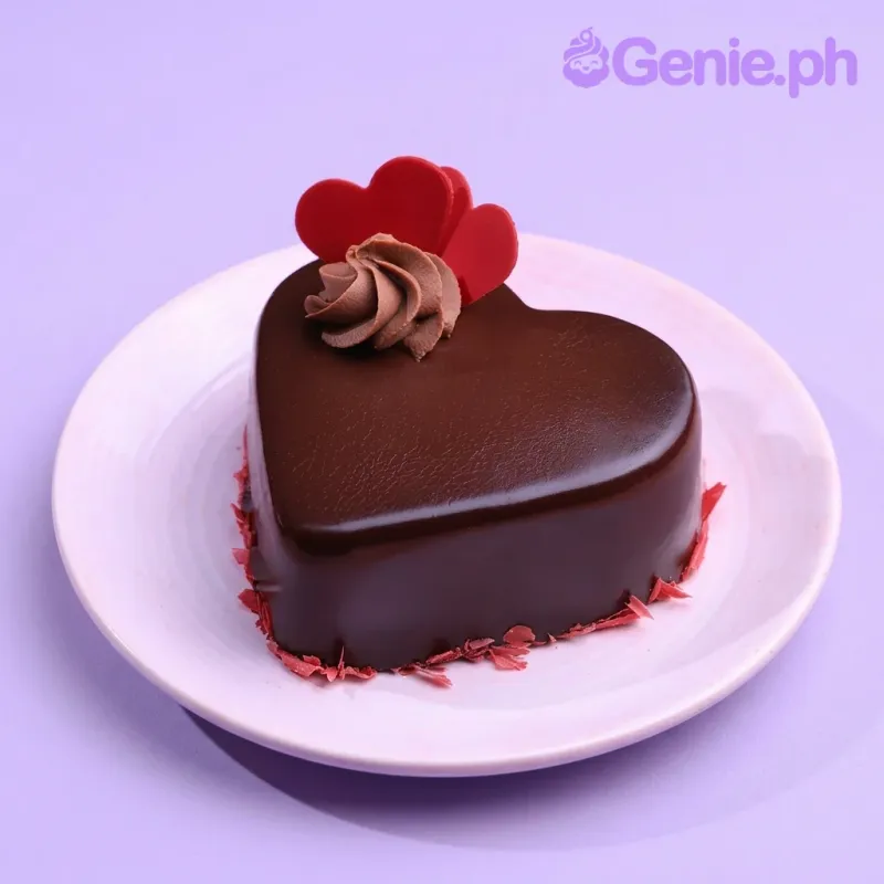 A brown heart-shaped cake with red accents, featuring two red fondant hearts, a chocolate buttercream swirl, and red chocolate shavings. A brown heart-shaped cake with red accents, featuring two red fondant hearts, a chocolate buttercream swirl, and red chocolate shavings.