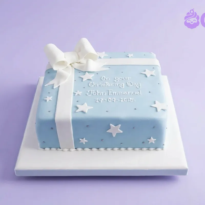 Light blue square fondant cake designed as a gift box with a large white fondant bow, white star accents, and silver dragees. Light blue square fondant cake designed as a gift box with a large white fondant bow, white star accents, and silver dragees.