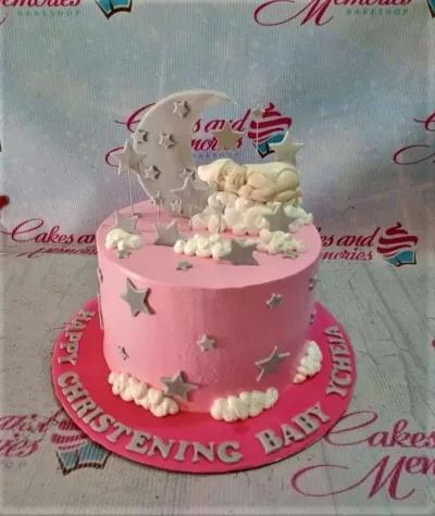 Pink christening cake for a baby girl featuring a sleeping baby on clouds, a large crescent moon, and silver stars. Pink christening cake for a baby girl featuring a sleeping baby on clouds, a large crescent moon, and silver stars.