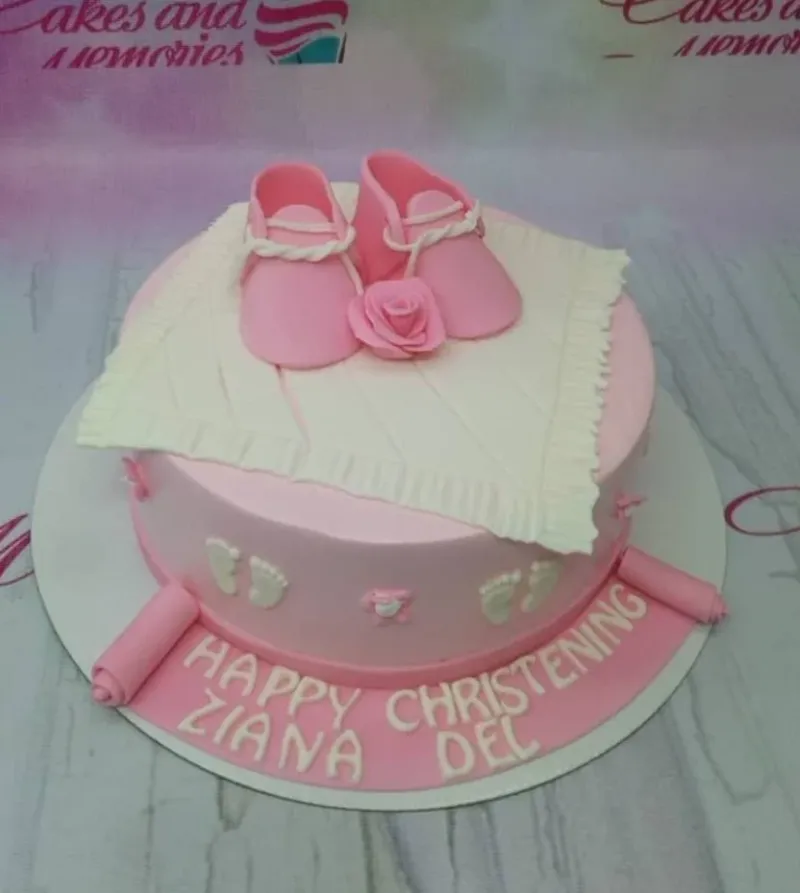 Pink fondant christening cake with edible baby shoes, a rose, and white baby footprints on the side. Pink fondant christening cake with edible baby shoes, a rose, and white baby footprints on the side.