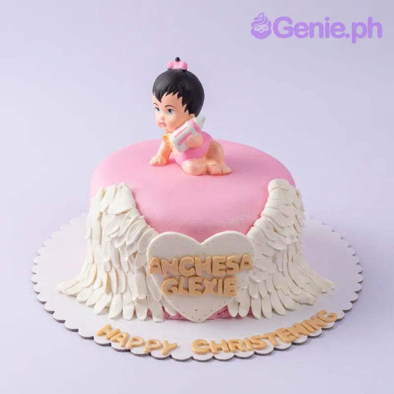 Pink fondant christening cake with a 3D baby girl topper, white angel wings, and a heart-shaped name plaque. Pink fondant christening cake with a 3D baby girl topper, white angel wings, and a heart-shaped name plaque.