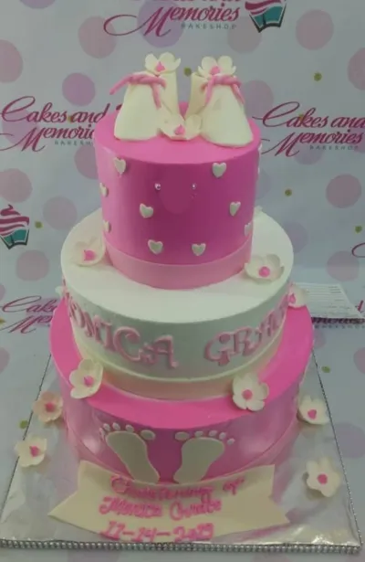 Pink and white 3-tier christening cake with fondant baby shoes, flowers, and baby footprints. Pink and white 3-tier christening cake with fondant baby shoes, flowers, and baby footprints.
