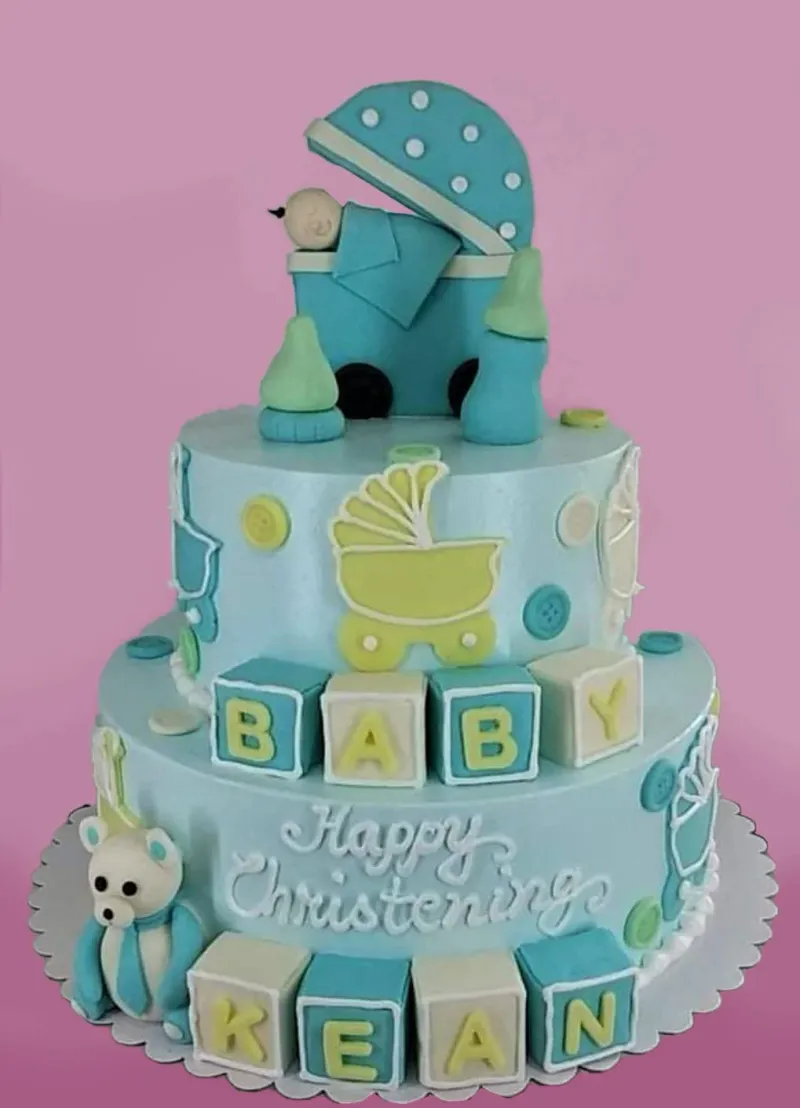 Blue 2-tier baby christening cake with a fondant baby carriage topper, alphabet blocks, and a teddy bear. Blue 2-tier baby christening cake with a fondant baby carriage topper, alphabet blocks, and a teddy bear.