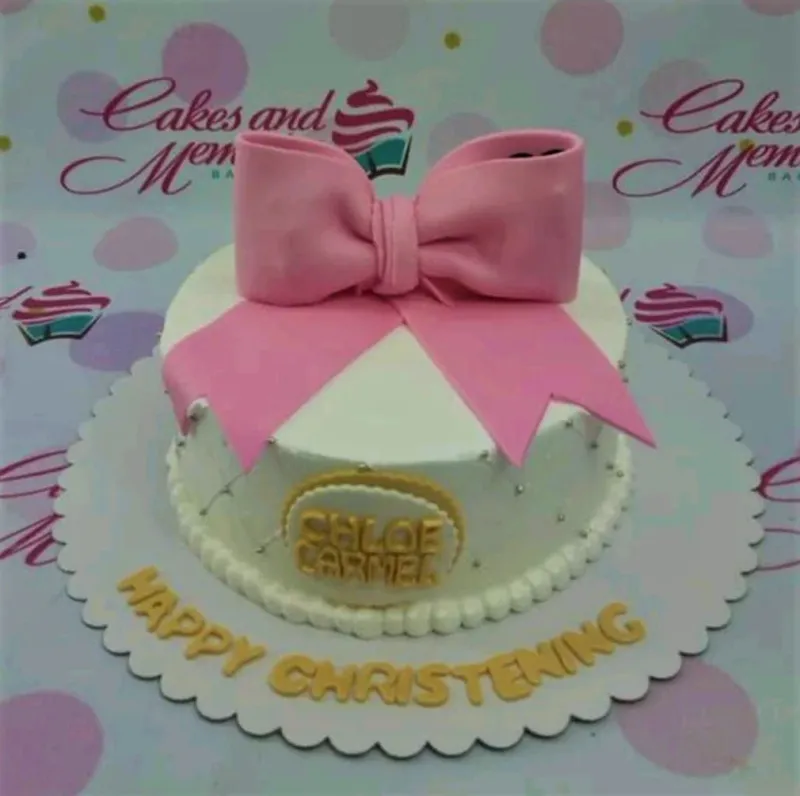 White round cake with a large pink fondant bow on top and gold gumpaste letters on the base board. White round cake with a large pink fondant bow on top and gold gumpaste letters on the base board.