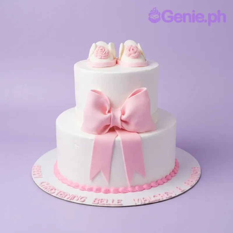 Two-tier white fondant christening cake with a large pink bow and edible pink baby shoes on top. Two-tier white fondant christening cake with a large pink bow and edible pink baby shoes on top.