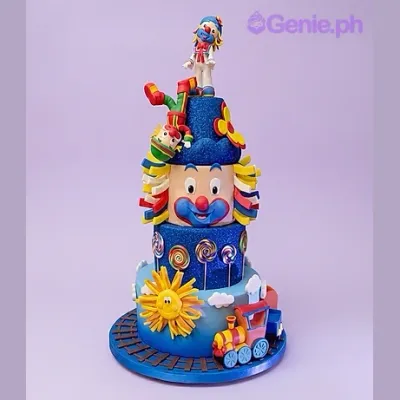 Blue 3-tier fondant cake with clown figurine topper and train decoration Blue 3-tier fondant cake with clown figurine topper and train decoration