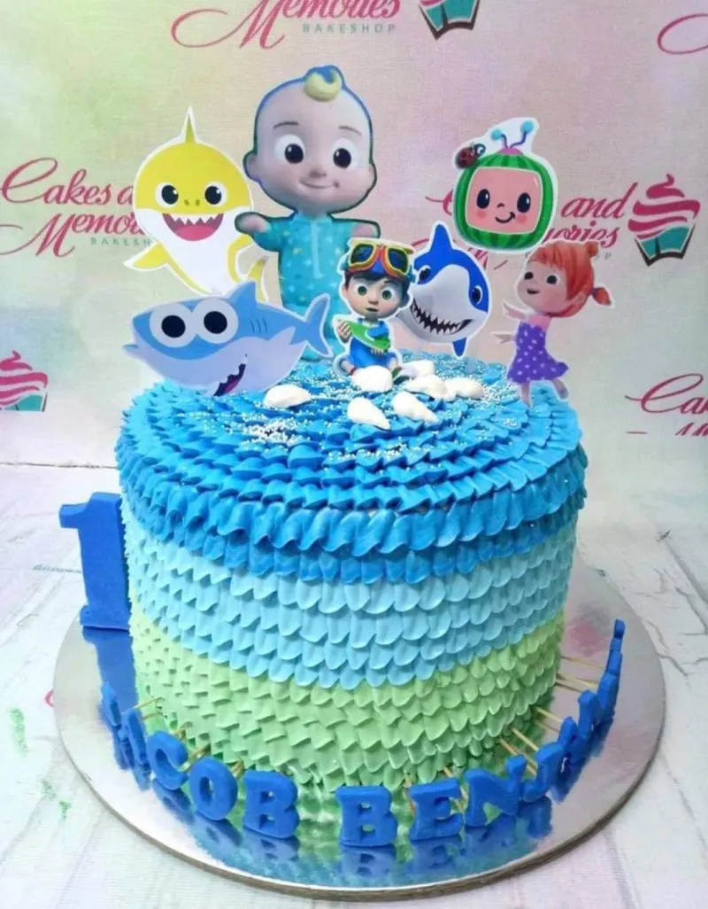 Cocomelon and Baby Shark themed birthday cake with blue and green ruffled icing and character printouts. Cocomelon and Baby Shark themed birthday cake with blue and green ruffled icing and character printouts.