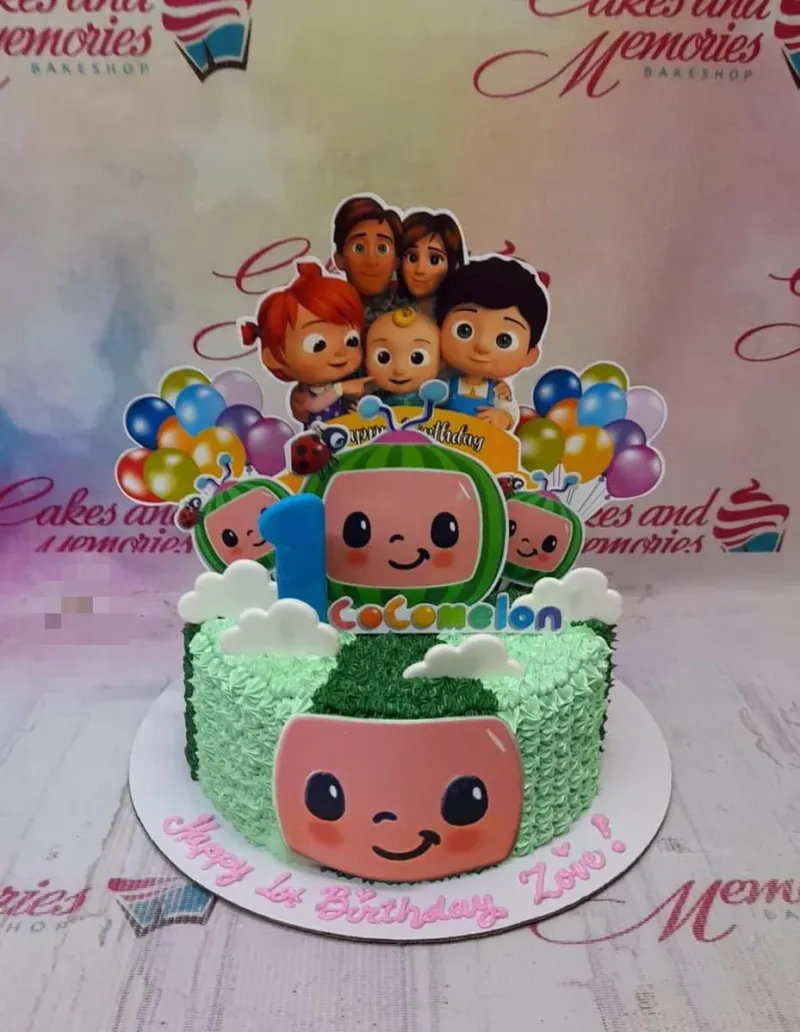 Cocomelon themed birthday cake with green textured icing, character printouts, and a blue number one topper. Cocomelon themed birthday cake with green textured icing, character printouts, and a blue number one topper.