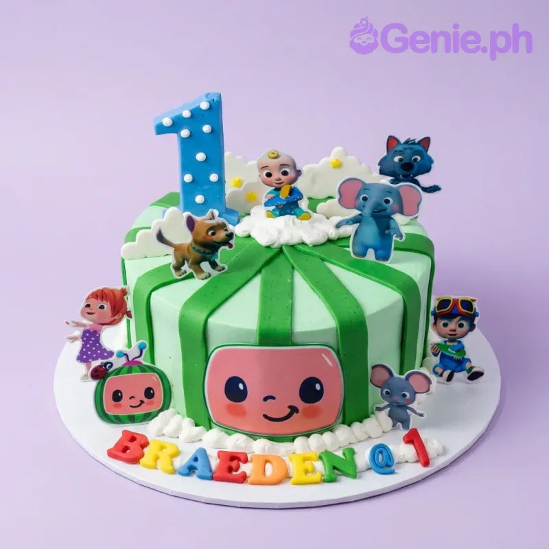 Cocomelon themed green striped cake with character printouts and a blue number one topper. Cocomelon themed green striped cake with character printouts and a blue number one topper.