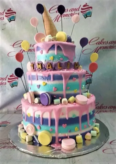 Three-tier colorful striped cake with pink drips, macarons, marshmallows, and balloon toppers for a birthday celebration. Three-tier colorful striped cake with pink drips, macarons, marshmallows, and balloon toppers for a birthday celebration.