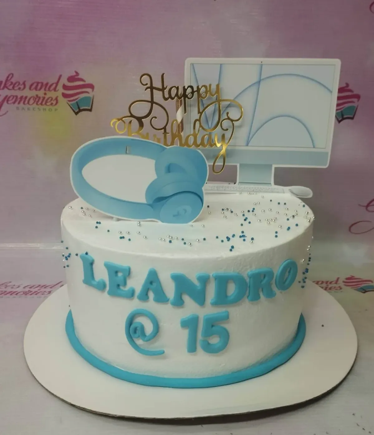 A white 1-tier cake themed for Computer Music, featuring a computer monitor, blue headphones, and blue and silver sprinkles. A white 1-tier cake themed for Computer Music, featuring a computer monitor, blue headphones, and blue and silver sprinkles.
