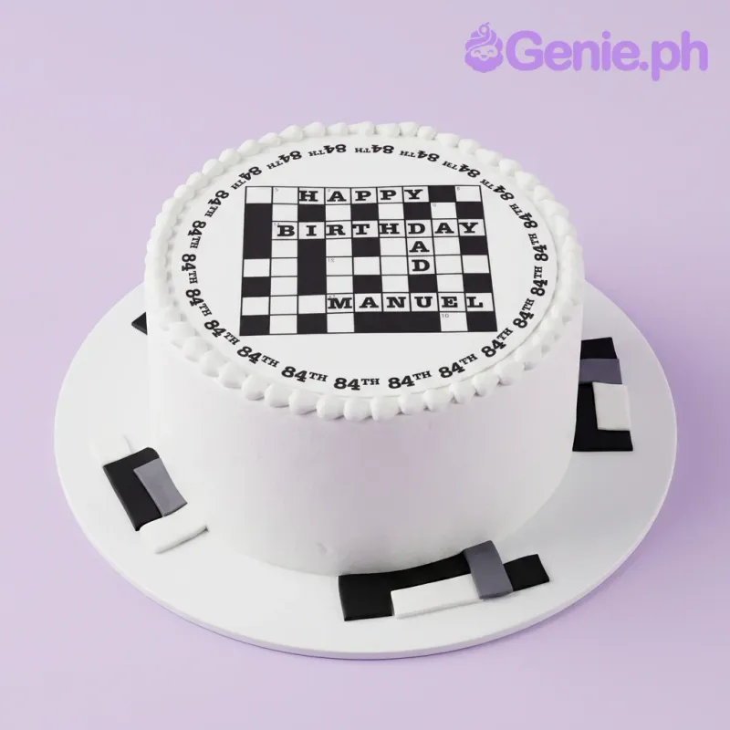 A white and black 1-tier crossword cake, featuring a crossword print, '84th' border, icing beads, geometric panels. A white and black 1-tier crossword cake, featuring a crossword print, '84th' border, icing beads, geometric panels.