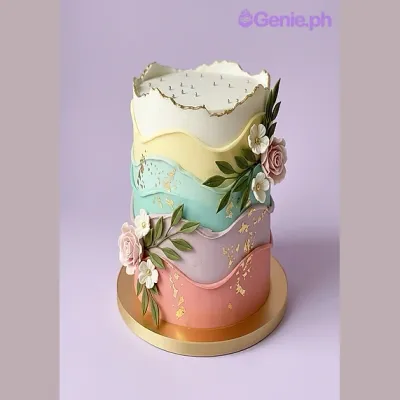 Multi-colored wavy fondant cake with edible flower clusters and gold leaf accents Multi-colored wavy fondant cake with edible flower clusters and gold leaf accents