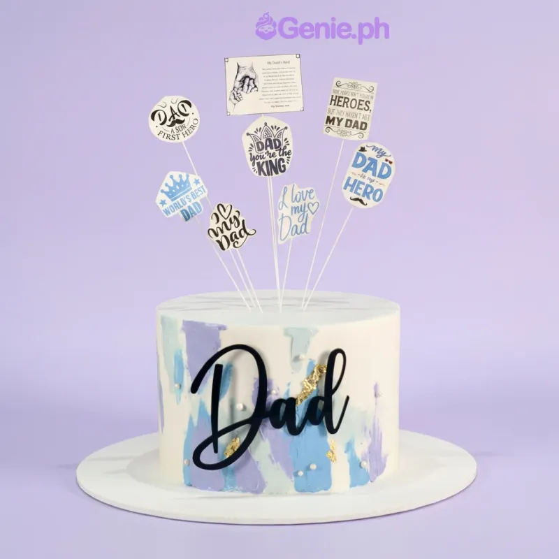 White single-tier cake with blue and purple painted icing accents and dad-themed printed toppers White single-tier cake with blue and purple painted icing accents and dad-themed printed toppers