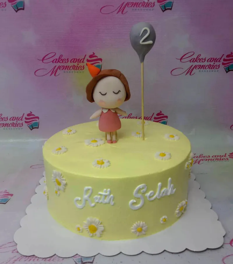 A yellow and white 1-tier Daisy Girl themed cake, featuring a fondant girl holding a grey number '2' balloon and icing daisies. A yellow and white 1-tier Daisy Girl themed cake, featuring a fondant girl holding a grey number '2' balloon and icing daisies.