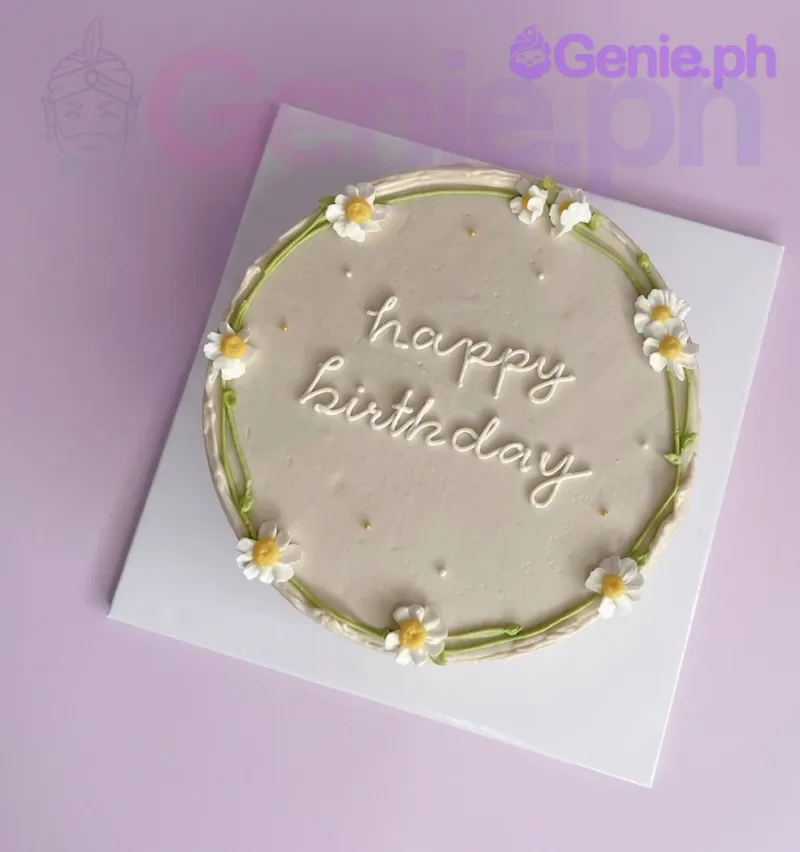 A beige 1 Tier cake themed Daisy Minimalist, featuring piped white and yellow daisies, a green vine, and 'happy birthday' text. A beige 1 Tier cake themed Daisy Minimalist, featuring piped white and yellow daisies, a green vine, and 'happy birthday' text.