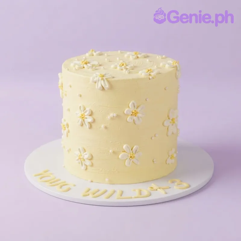 Soft light yellow 1-tier cake with smooth icing, piped white daisy flowers, and scattered sugar pearls Soft light yellow 1-tier cake with smooth icing, piped white daisy flowers, and scattered sugar pearls
