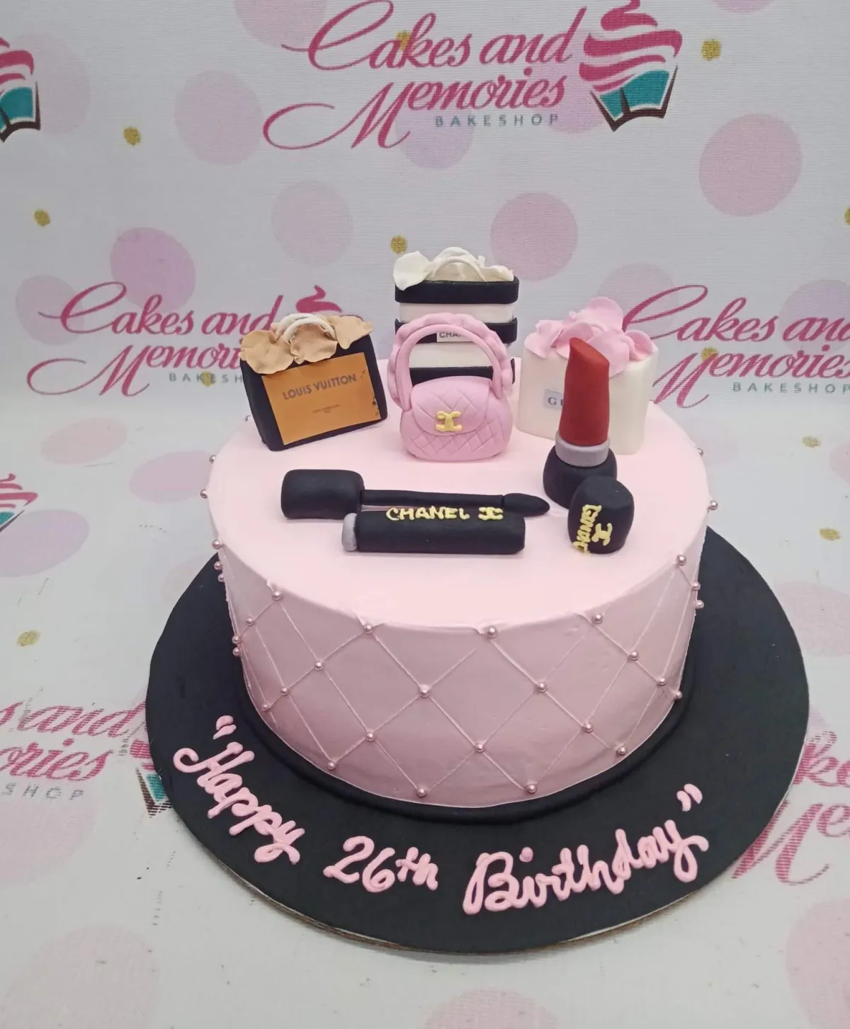 A pink 1-tier designer makeup cake with fondant shopping bags, a quilted handbag, lipstick, and a quilted icing pattern. A pink 1-tier designer makeup cake with fondant shopping bags, a quilted handbag, lipstick, and a quilted icing pattern.