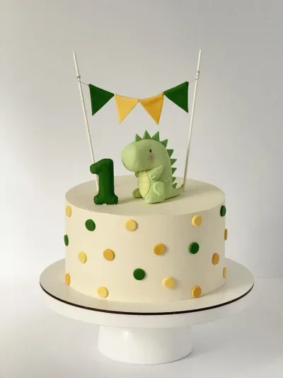 White 1-tier cake with soft icing, dinosaur theme, light green fondant dinosaur topper, and dark green fondant number one White 1-tier cake with soft icing, dinosaur theme, light green fondant dinosaur topper, and dark green fondant number one