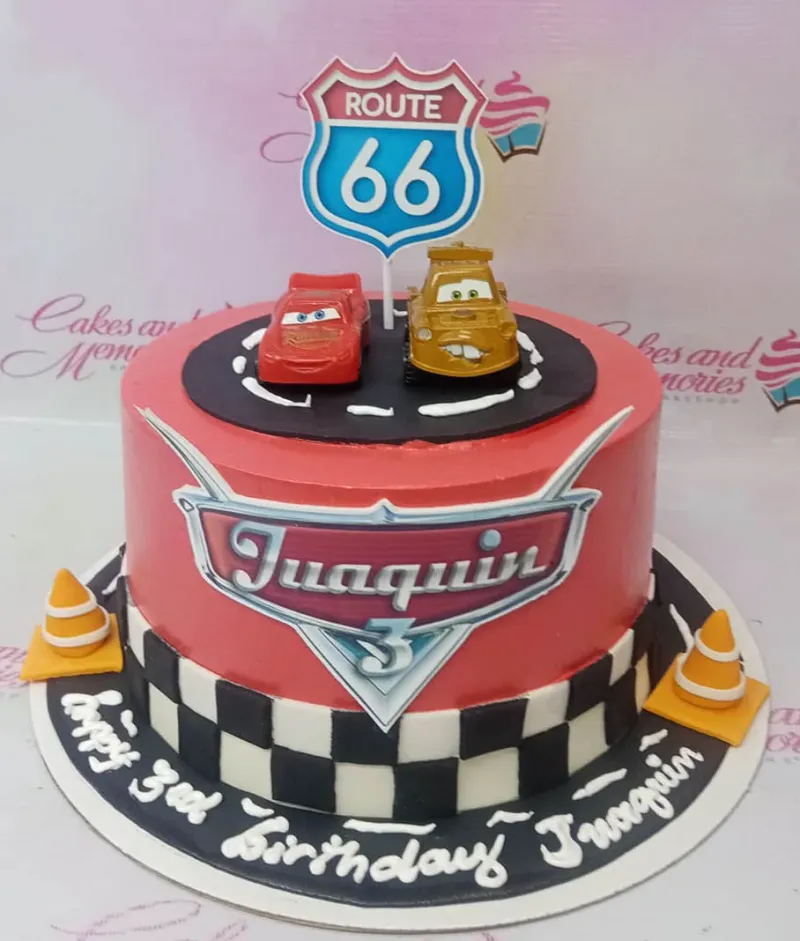 Red Disney Cars themed birthday cake with Lightning McQueen and Mater toy toppers, Route 66 sign, and checkered racing flag border. Red Disney Cars themed birthday cake with Lightning McQueen and Mater toy toppers, Route 66 sign, and checkered racing flag border.