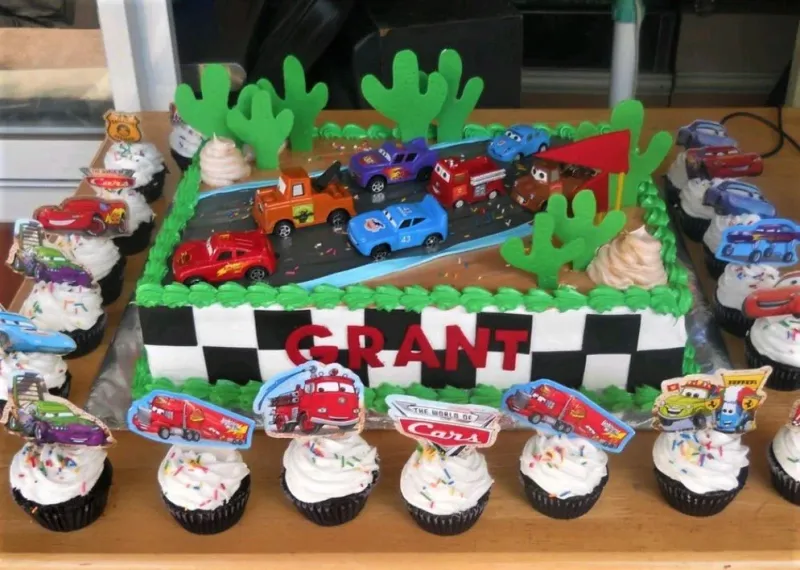Disney Cars themed rectangle cake with toy cars, green cactus toppers, and a checkered flag side design for Grant's birthday. Disney Cars themed rectangle cake with toy cars, green cactus toppers, and a checkered flag side design for Grant's birthday.