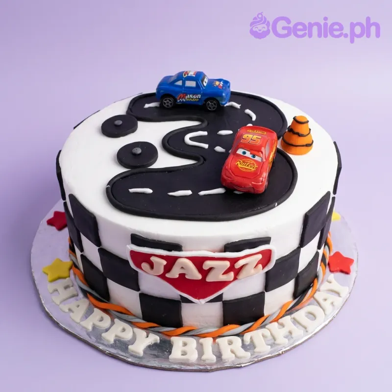 Disney Cars themed birthday cake with Lightning McQueen and Doc Hudson toy cars on a black fondant road with checkered flag toppers. Disney Cars themed birthday cake with Lightning McQueen and Doc Hudson toy cars on a black fondant road with checkered flag toppers.