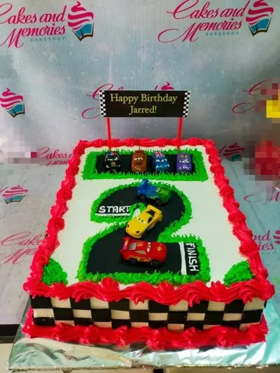 Disney Cars themed rectangle birthday cake with a number 2 racetrack design, toy cars, and red icing borders. Disney Cars themed rectangle birthday cake with a number 2 racetrack design, toy cars, and red icing borders.