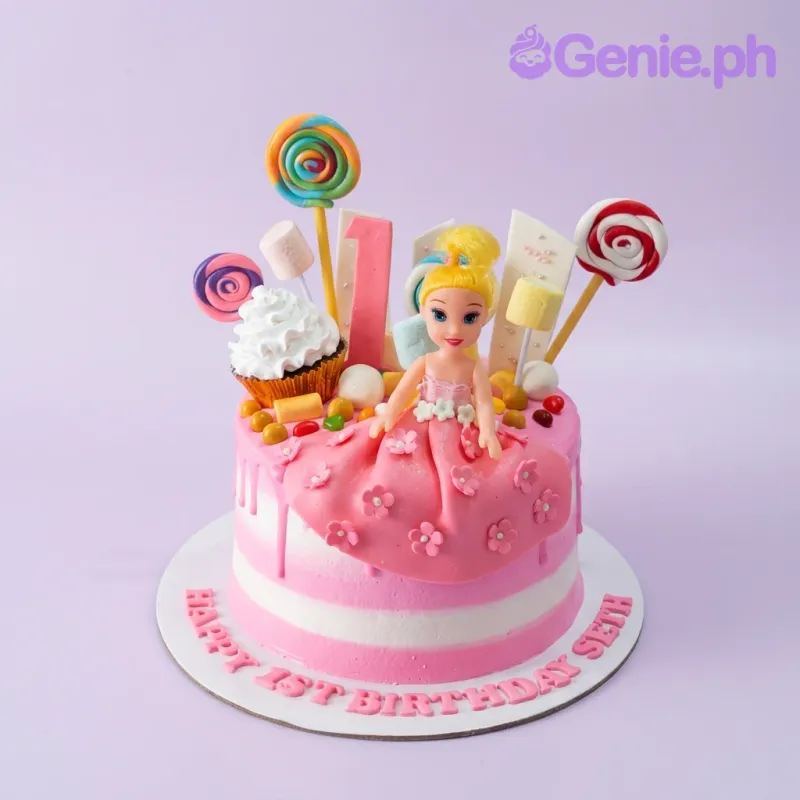 Pink and white striped doll cake with a blonde doll topper, lollipops, marshmallows, and a cupcake decoration. Pink and white striped doll cake with a blonde doll topper, lollipops, marshmallows, and a cupcake decoration.