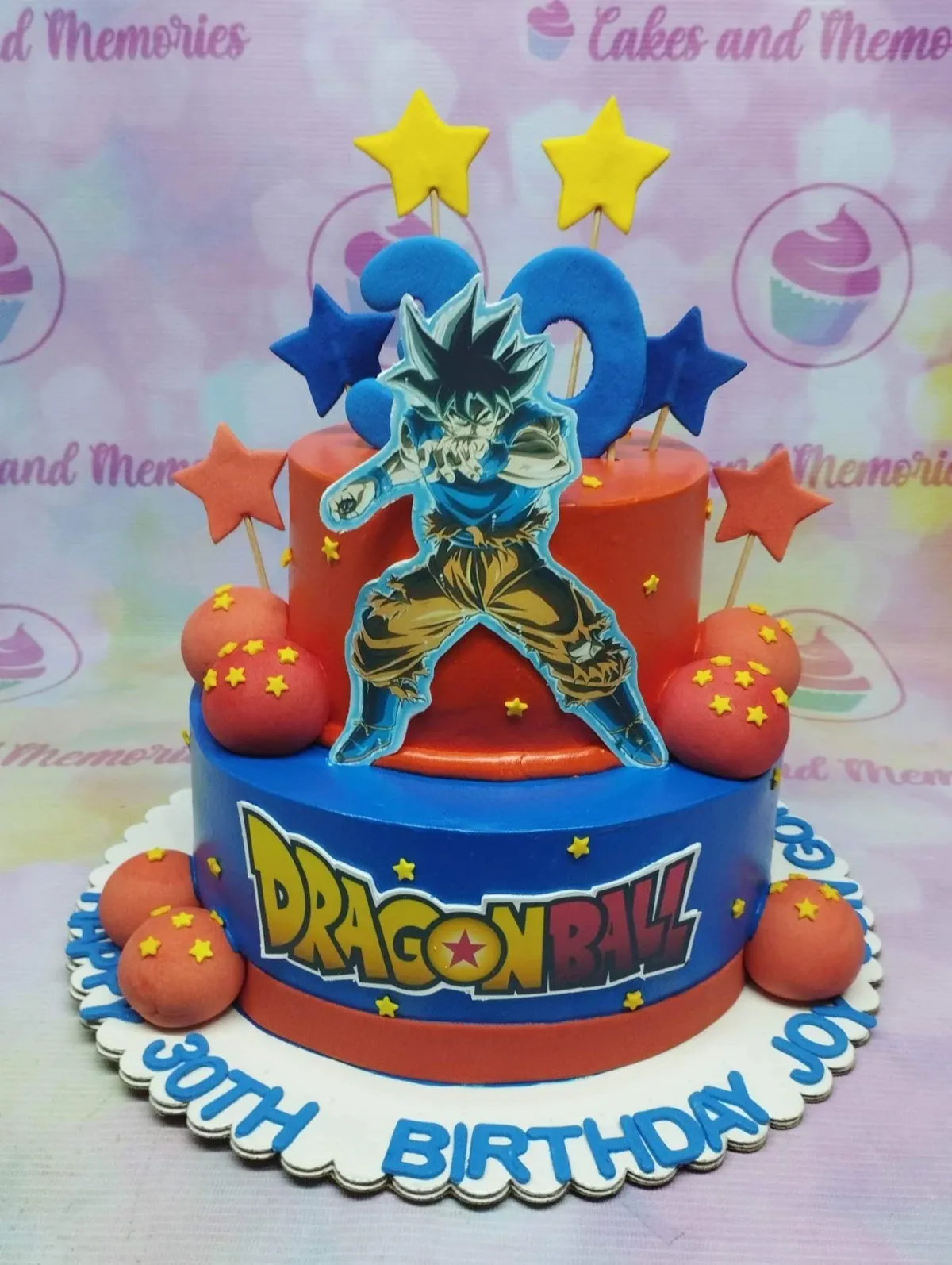 A orange and blue 2 Tier Fondant cake themed around Dragon Ball Z, featuring Goku, Dragon Ball logo, and fondant dragon balls. A orange and blue 2 Tier Fondant cake themed around Dragon Ball Z, featuring Goku, Dragon Ball logo, and fondant dragon balls.