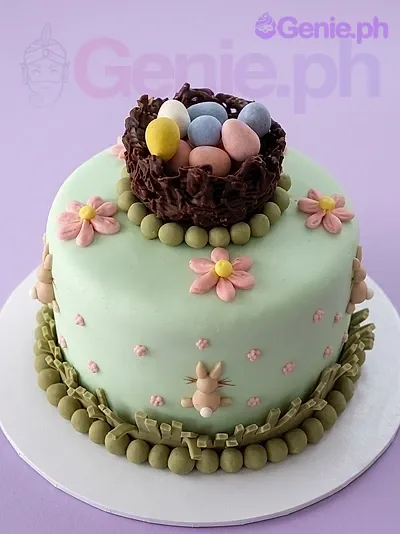 A light green 1-tier fondant Easter Bird Nest cake, featuring a chocolate bird nest with eggs, pink flowers, and a small bunny. A light green 1-tier fondant Easter Bird Nest cake, featuring a chocolate bird nest with eggs, pink flowers, and a small bunny.