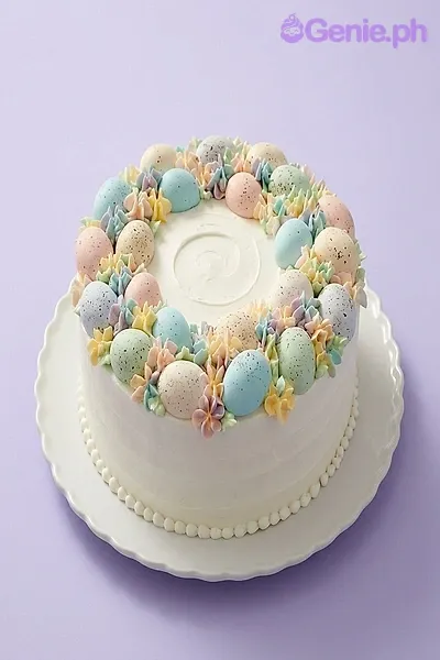 A white 1-tier cake themed around Easter Speckled Eggs, featuring pastel speckled eggs and icing flowers. A white 1-tier cake themed around Easter Speckled Eggs, featuring pastel speckled eggs and icing flowers.