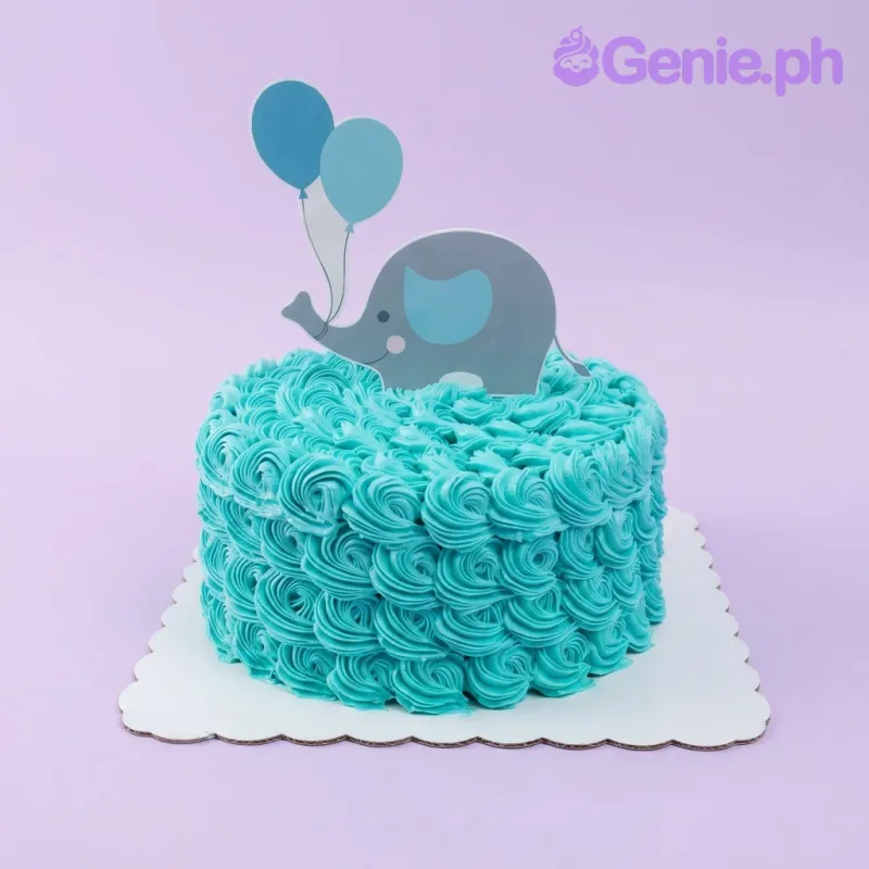 A teal and white 1-tier cake for an Elephant Christening, featuring a grey elephant and teal balloon printout, teal rosettes, a light blue message. A teal and white 1-tier cake for an Elephant Christening, featuring a grey elephant and teal balloon printout, teal rosettes, a light blue message.