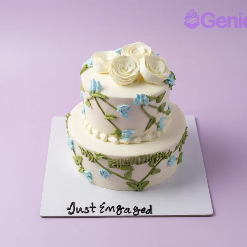 White 2-tier engagement cake with white roses and blue piped flowers White 2-tier engagement cake with white roses and blue piped flowers