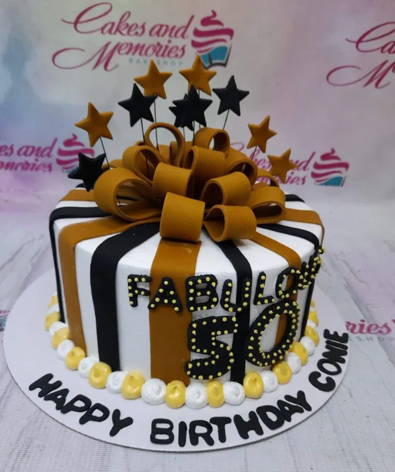A black and gold 1-tier cake themed around Fabulous 50, featuring a large gold bow, black and gold stars, and "FABULOUS 50" text. A black and gold 1-tier cake themed around Fabulous 50, featuring a large gold bow, black and gold stars, and "FABULOUS 50" text.