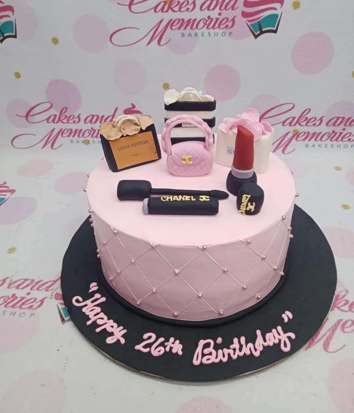 Pink 1-tier fashion themed birthday cake with fondant makeup and luxury shopping bag toppers on a black base board. Pink 1-tier fashion themed birthday cake with fondant makeup and luxury shopping bag toppers on a black base board.
